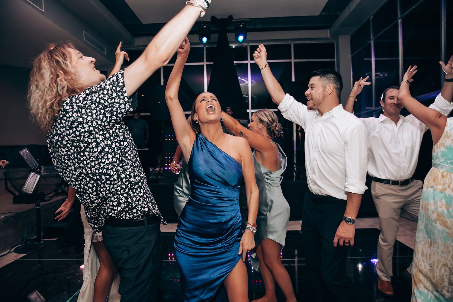 Lively dance party with guests in formal attire enjoying themselves under indoor lighting.