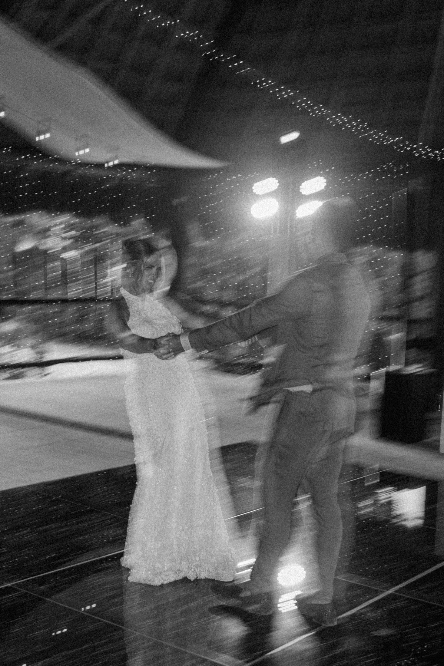 Blurred black and white photo of a bride and groom sharing their first dance at a Playa del Carmen wedding reception with string lights.