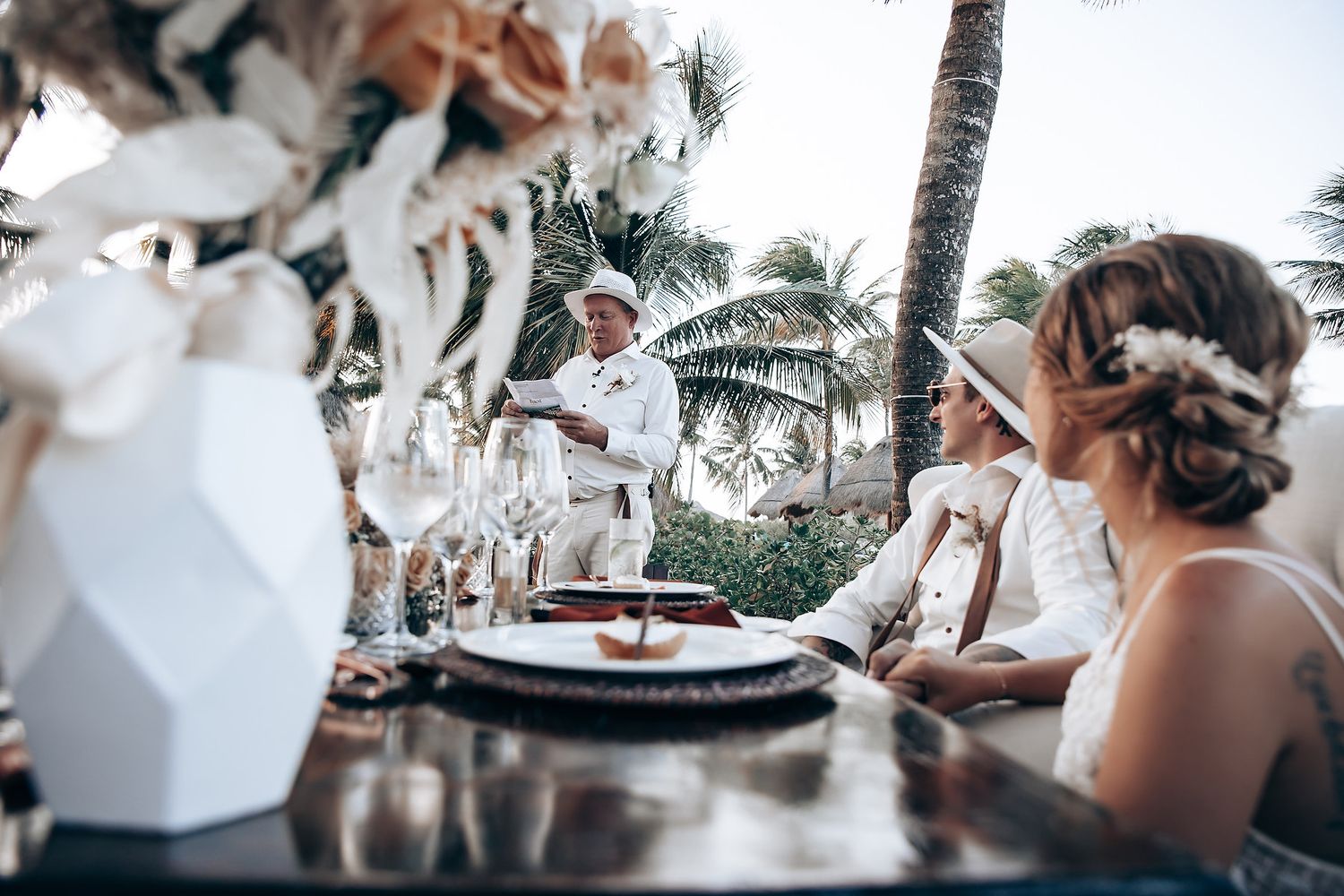 Outdoor tropical wedding reception setup with palm trees visible in the background.
