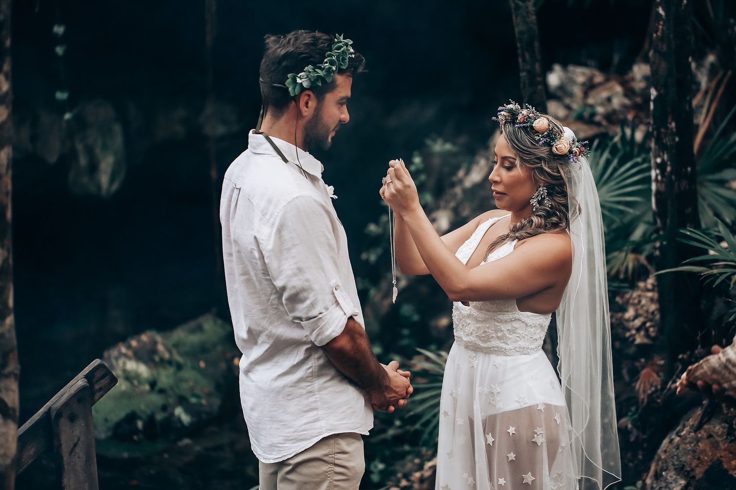 A romantic wedding moment captured in a natural forest setting with floral crowns and bohemian style.
