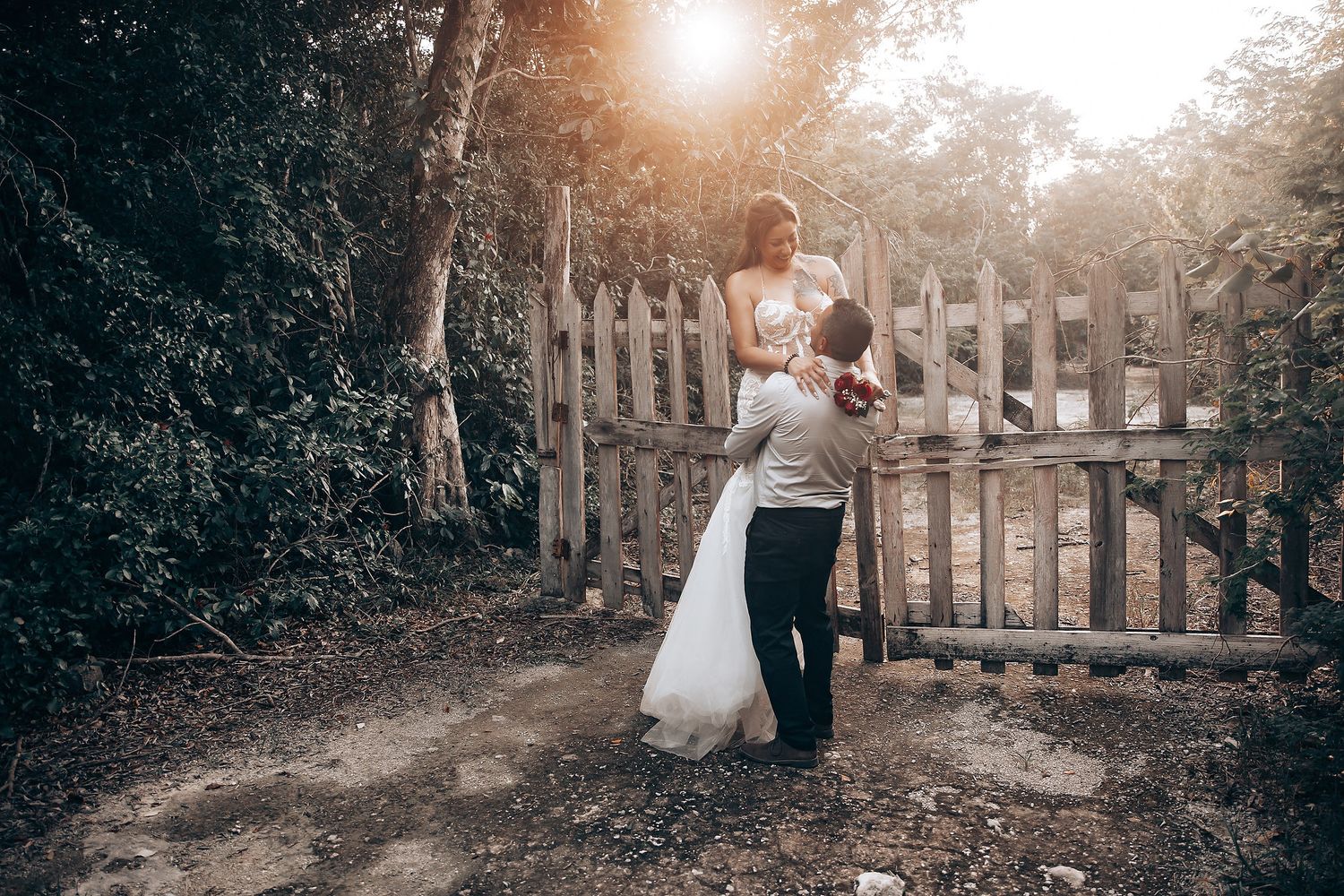 A sunset wedding photo session with a wooden fence and golden light filtering through trees.