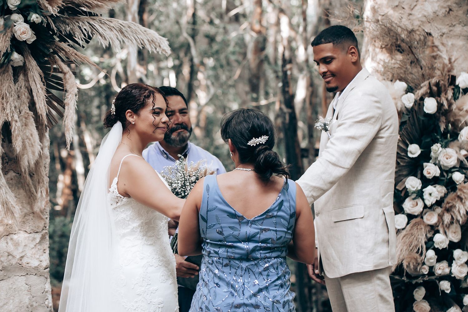 Wedding guests and bridal party interact in a rustic outdoor setting with trees.