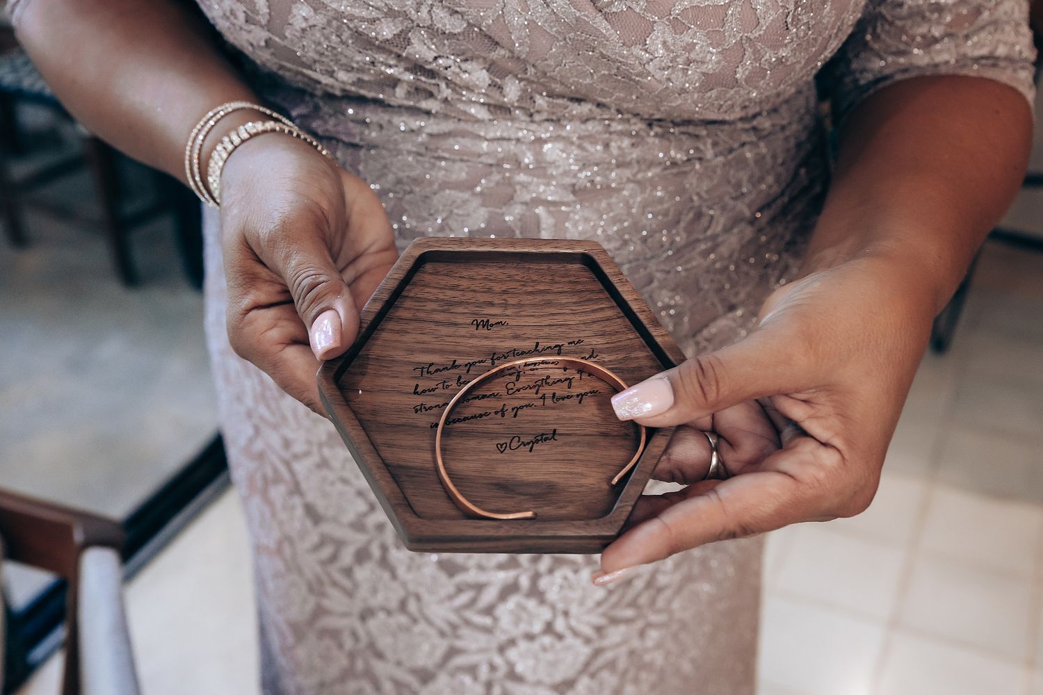 Hands holding a wooden hexagonal ring box with engraved moon design.