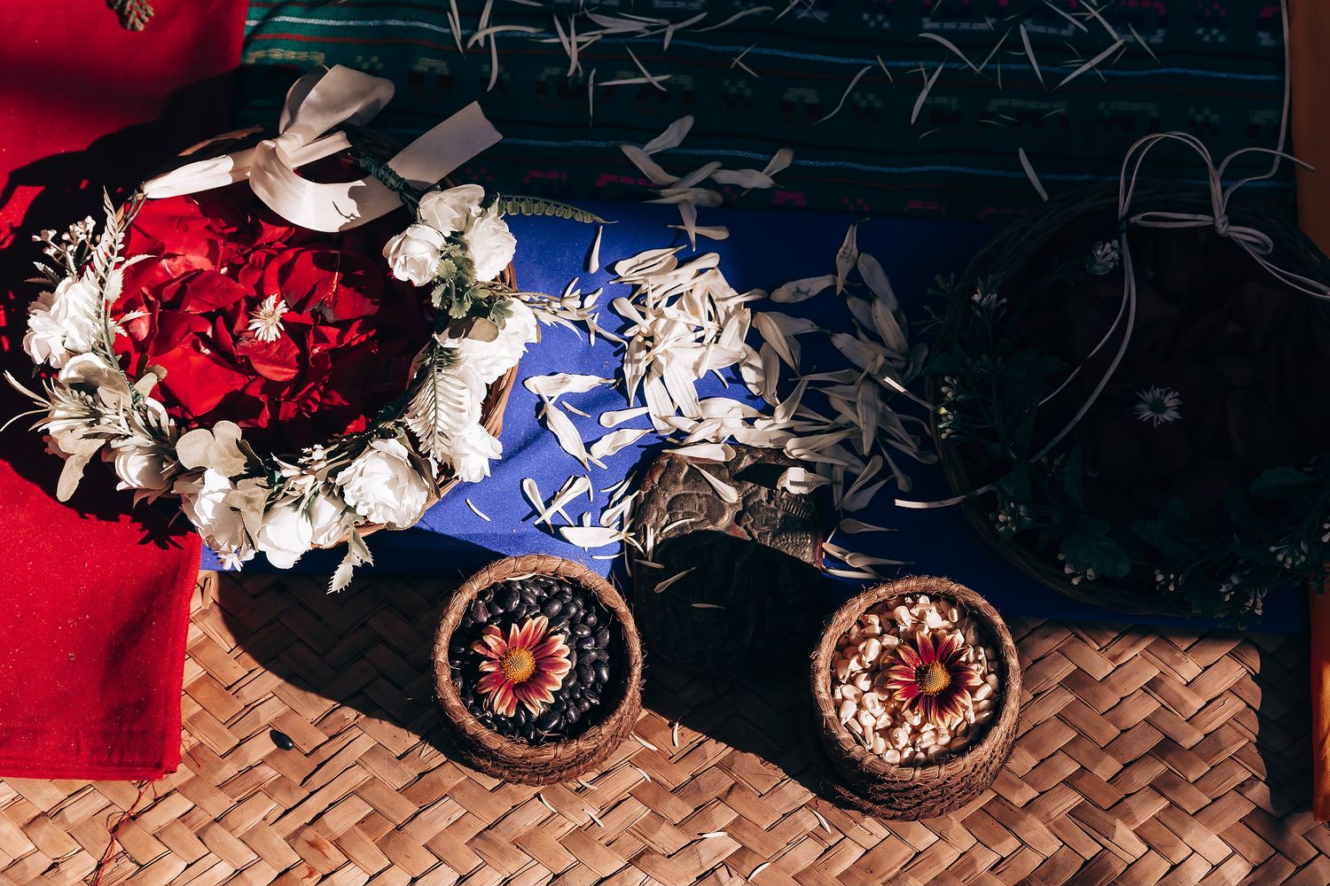 Colorful collection of jewelry and accessories displayed on woven bamboo surfaces with red and blue fabrics.