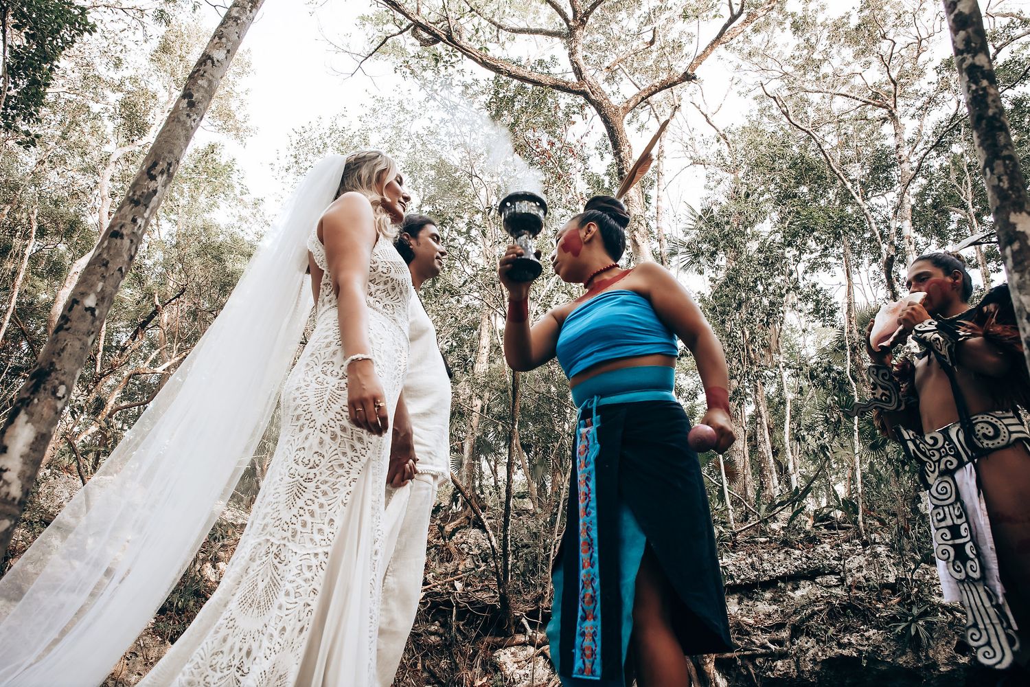 A dreamy outdoor wedding ceremony scene with guests gathered among birch trees in a natural woodland setting.
