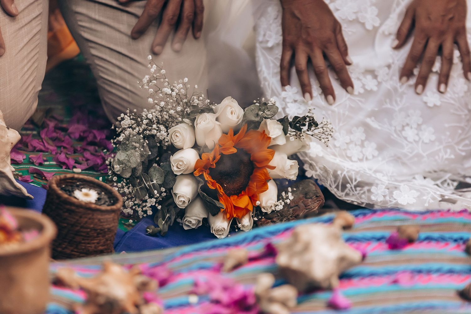 Traditional Mexican wedding ceremony with copal smoke and flower petals being scattered on colorful textiles.