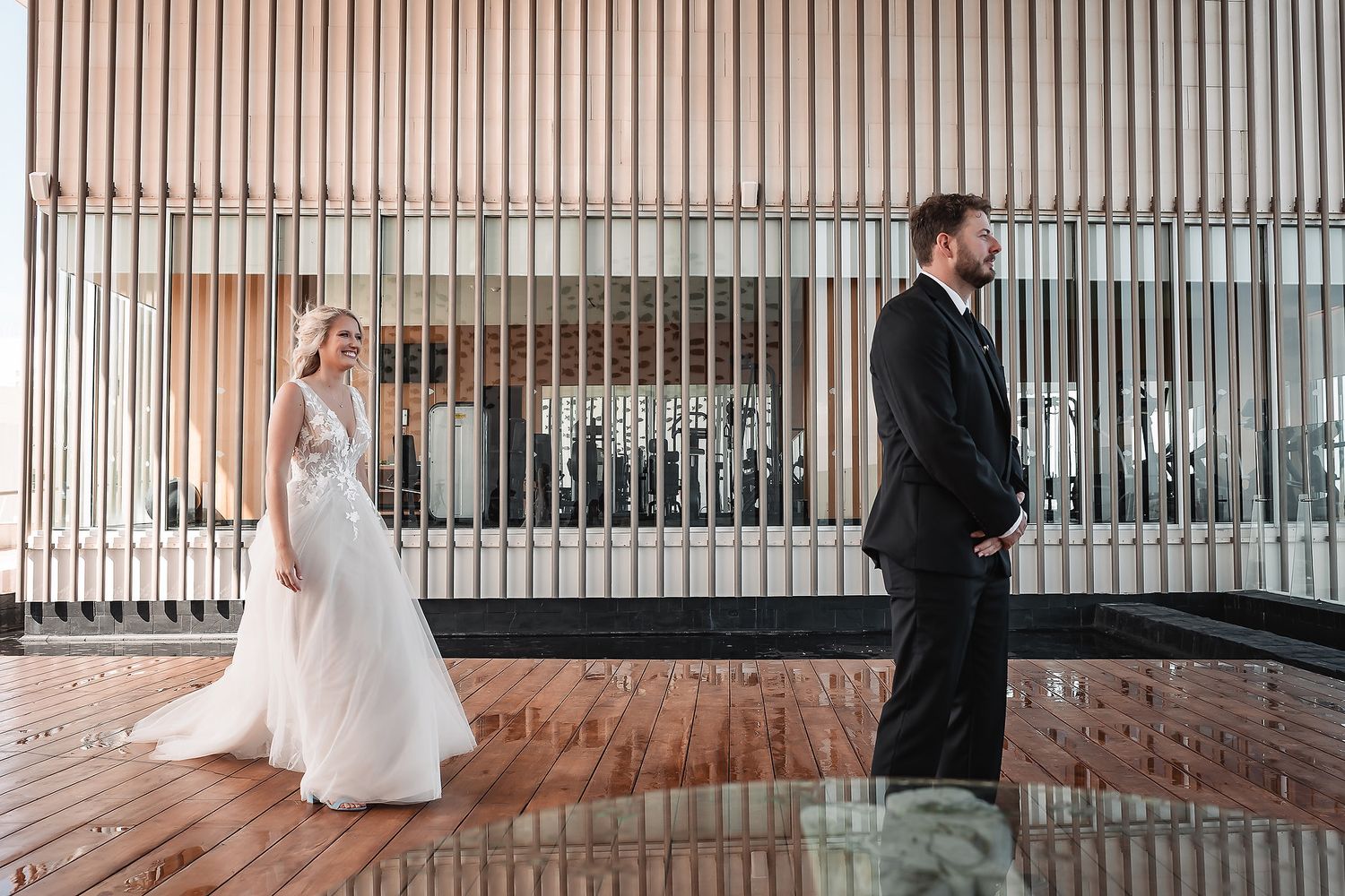 Wedding couple walking through a modern hallway with vertical striped walls.