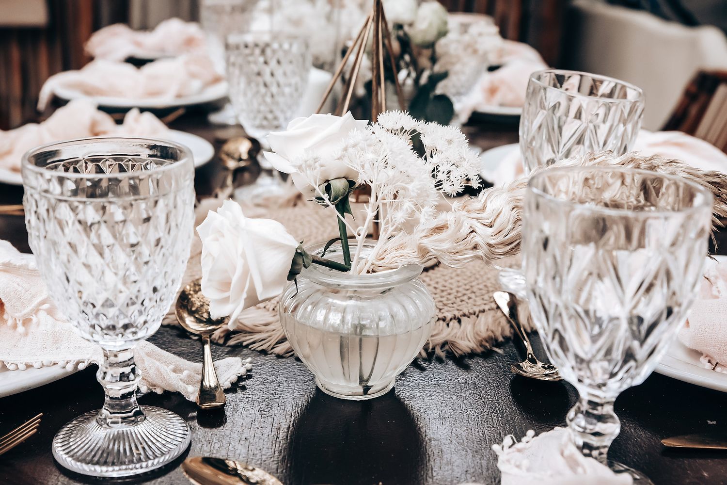 Elegant wedding table setting with crystal glasses and delicate floral centerpieces.