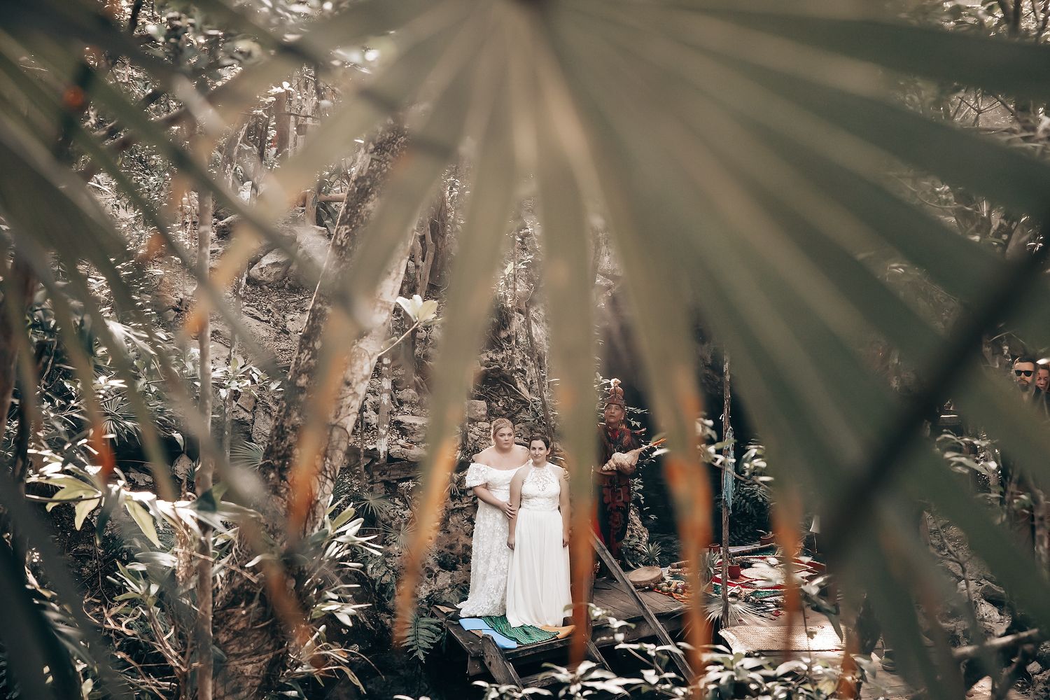 The image depicts a woman standing in a lush, forested environment, with sunlight streaming through the trees.
