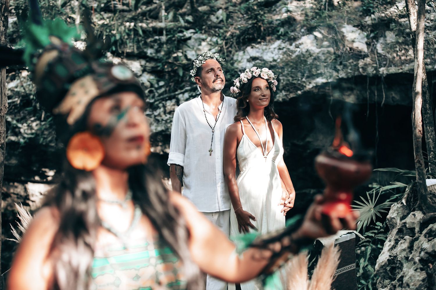 Two people, a man and a woman, standing in a lush, green forest.
