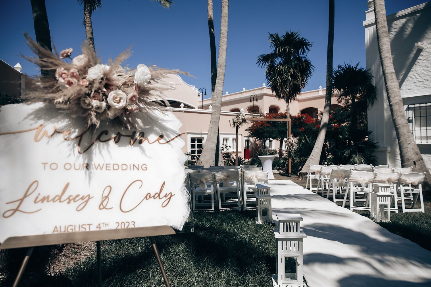 A wedding ceremony setup with chairs and a floral arch is visible in an outdoor setting.