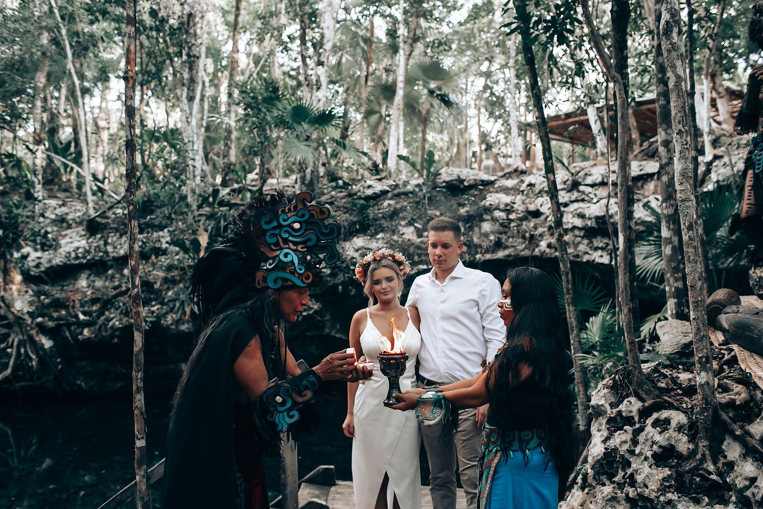 A group celebrates joyfully in an outdoor wooded setting during what appears to be a special occasion.