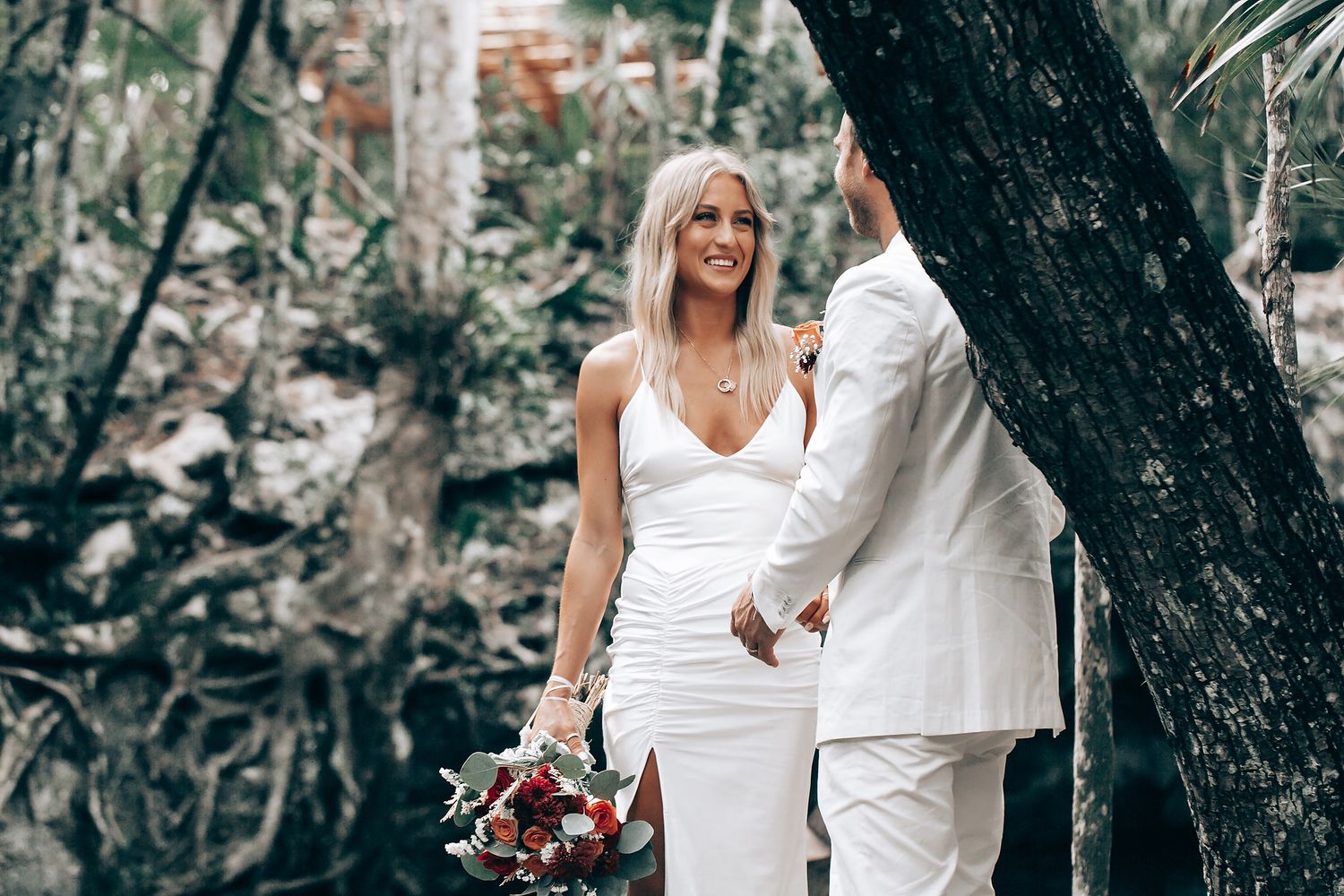 A romantic wedding portrait captured in a natural forest setting with soft lighting.