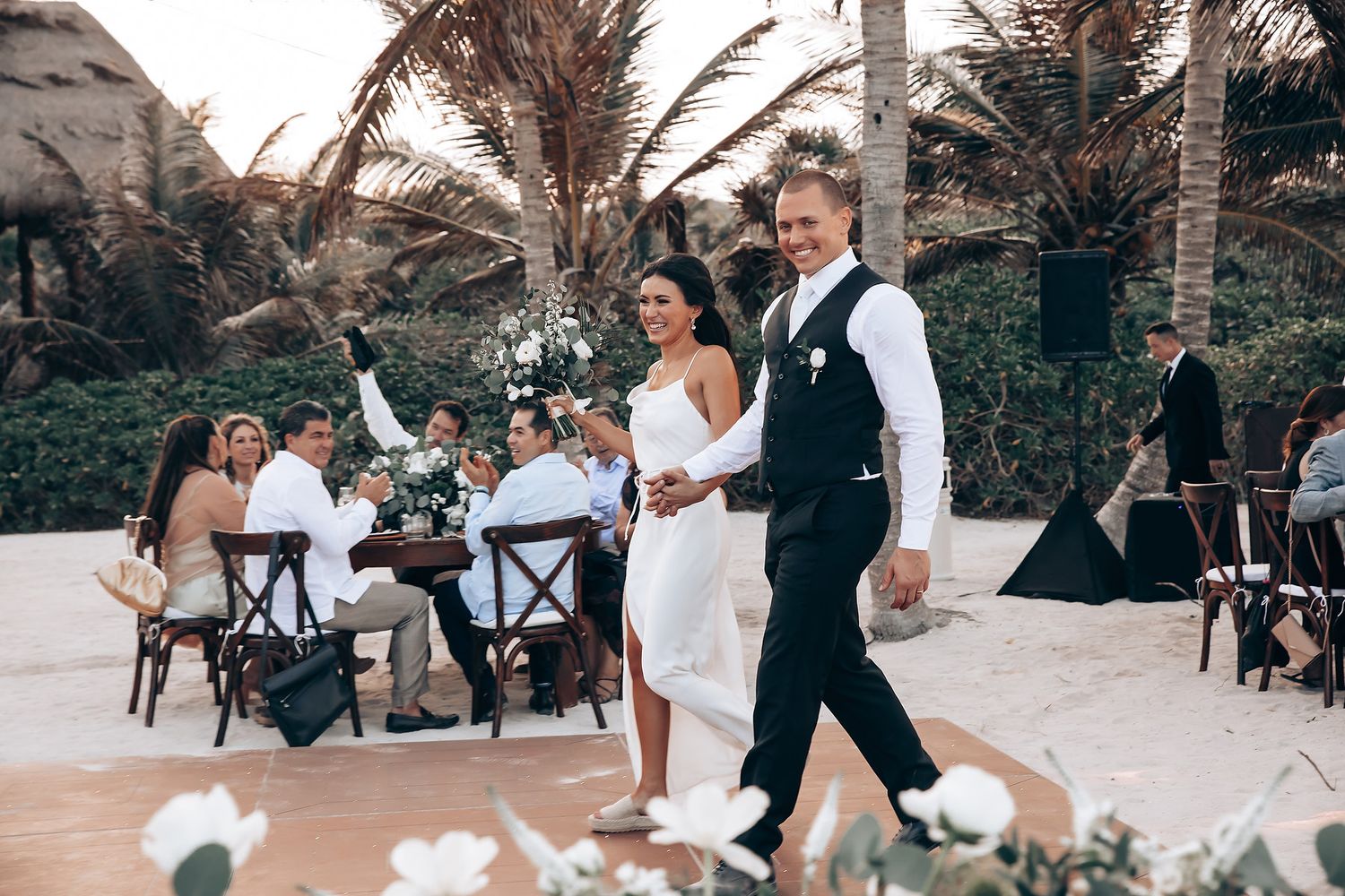 Wedding party and guests celebrating on an outdoor dance floor surrounded by nature.