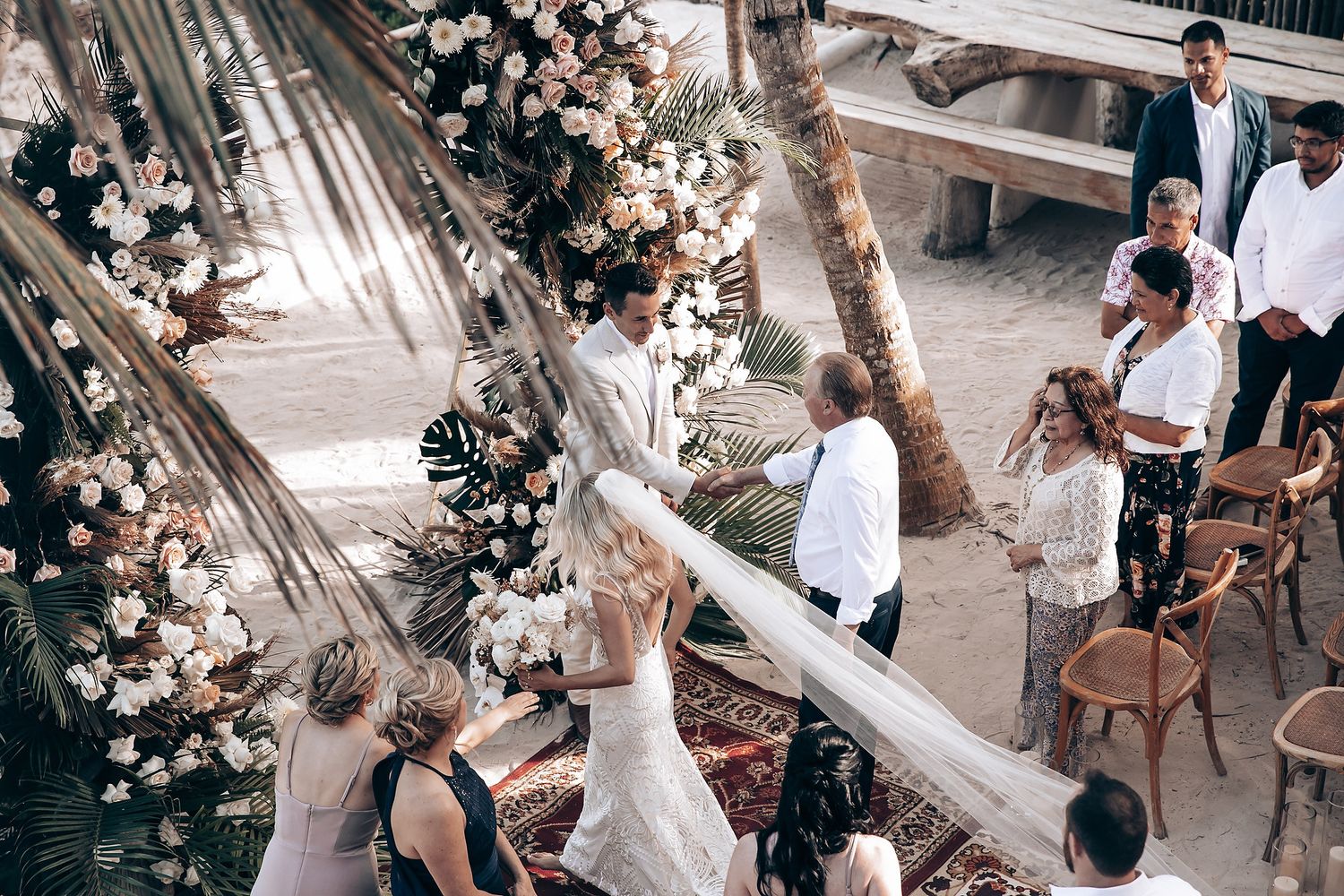 Overhead view of an elegant outdoor wedding ceremony with floral decorations and wooden chairs on a patio.