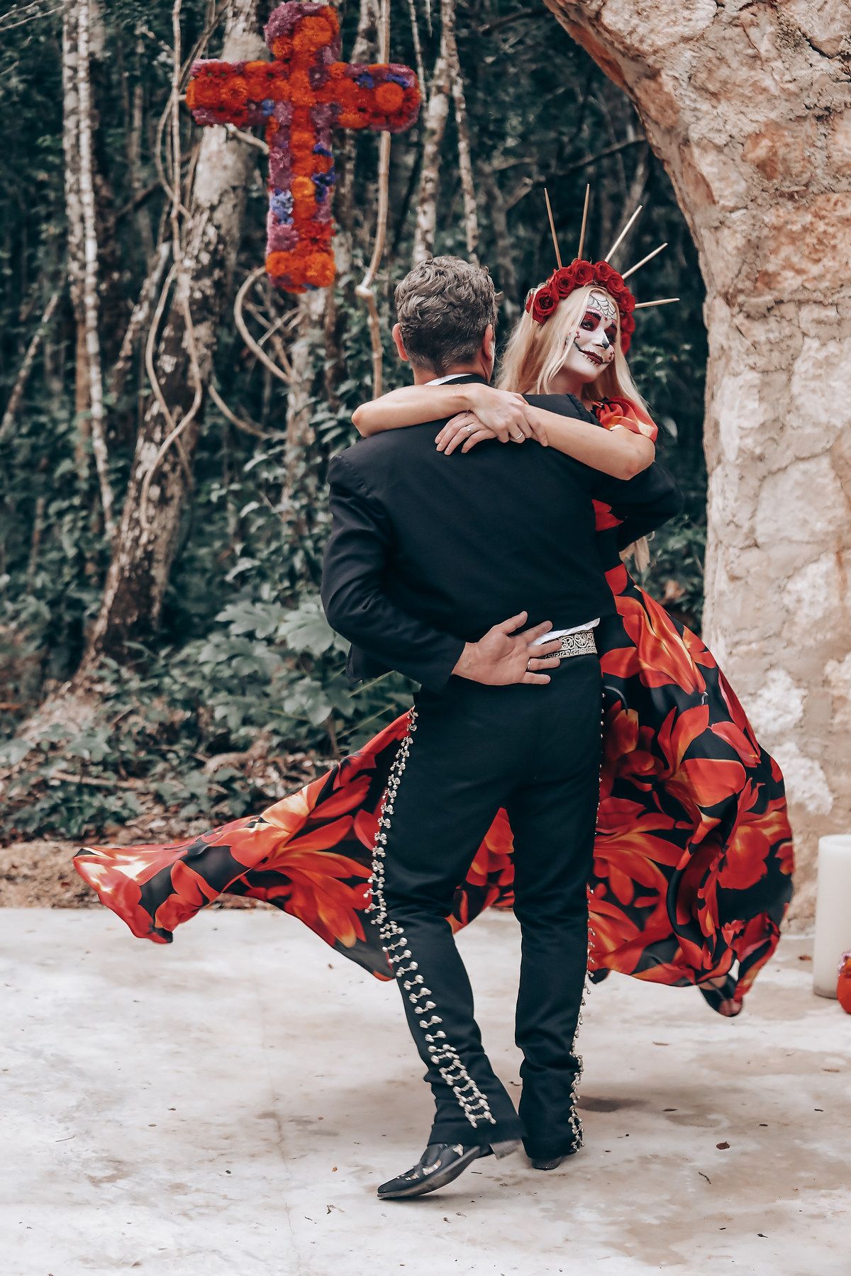 Dramatic dance pose showing flowing red dress and black boots against forest backdrop.