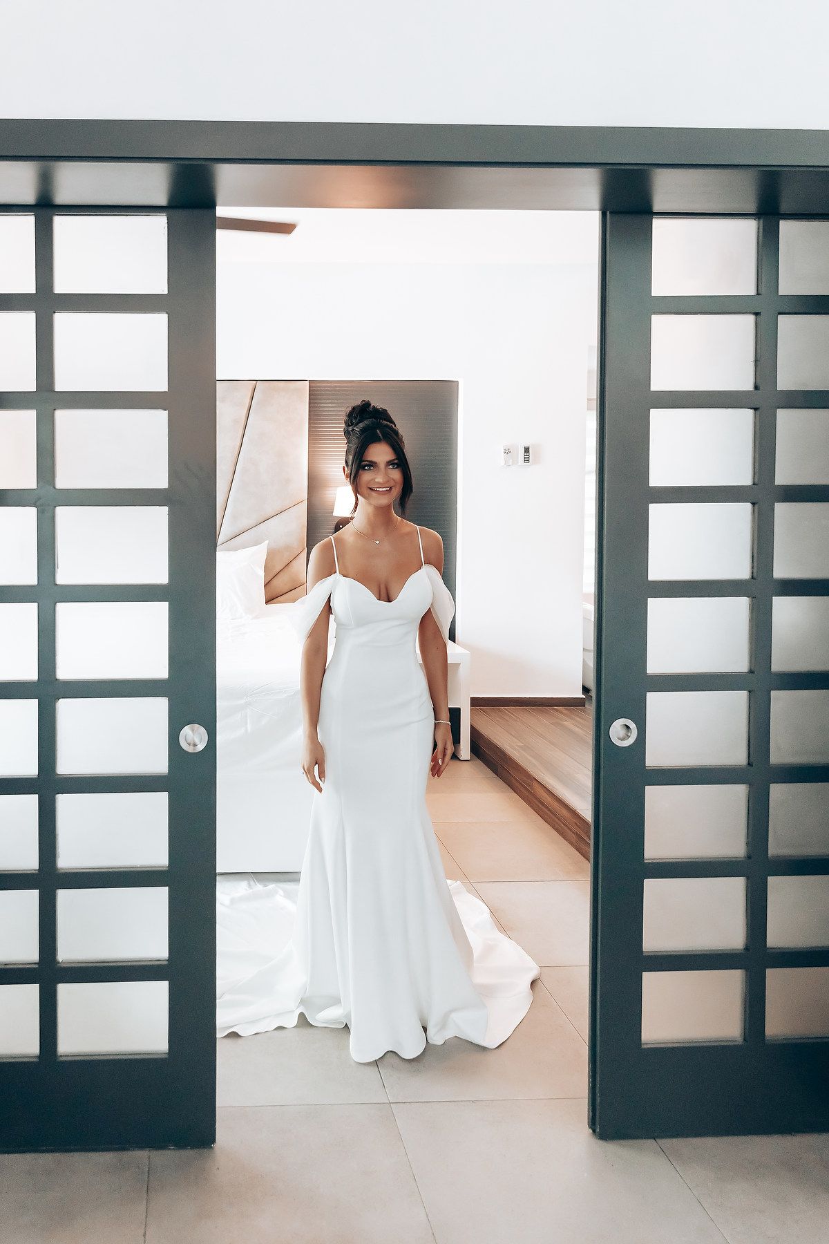 White wedding dress photographed through modern sliding doors in a minimalist setting.