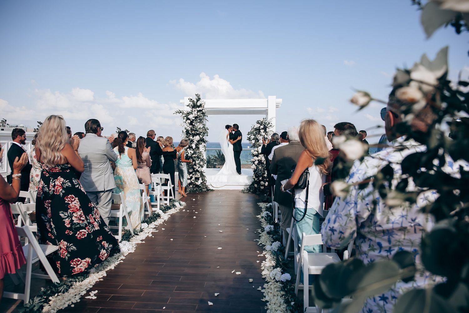 Wedding ceremony on elevated wooden deck overlooking scenic landscape.