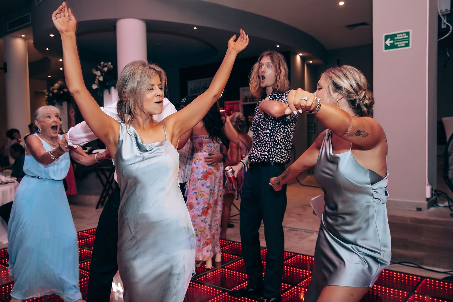 Party guests dancing energetically with raised arms on a festive dance floor.