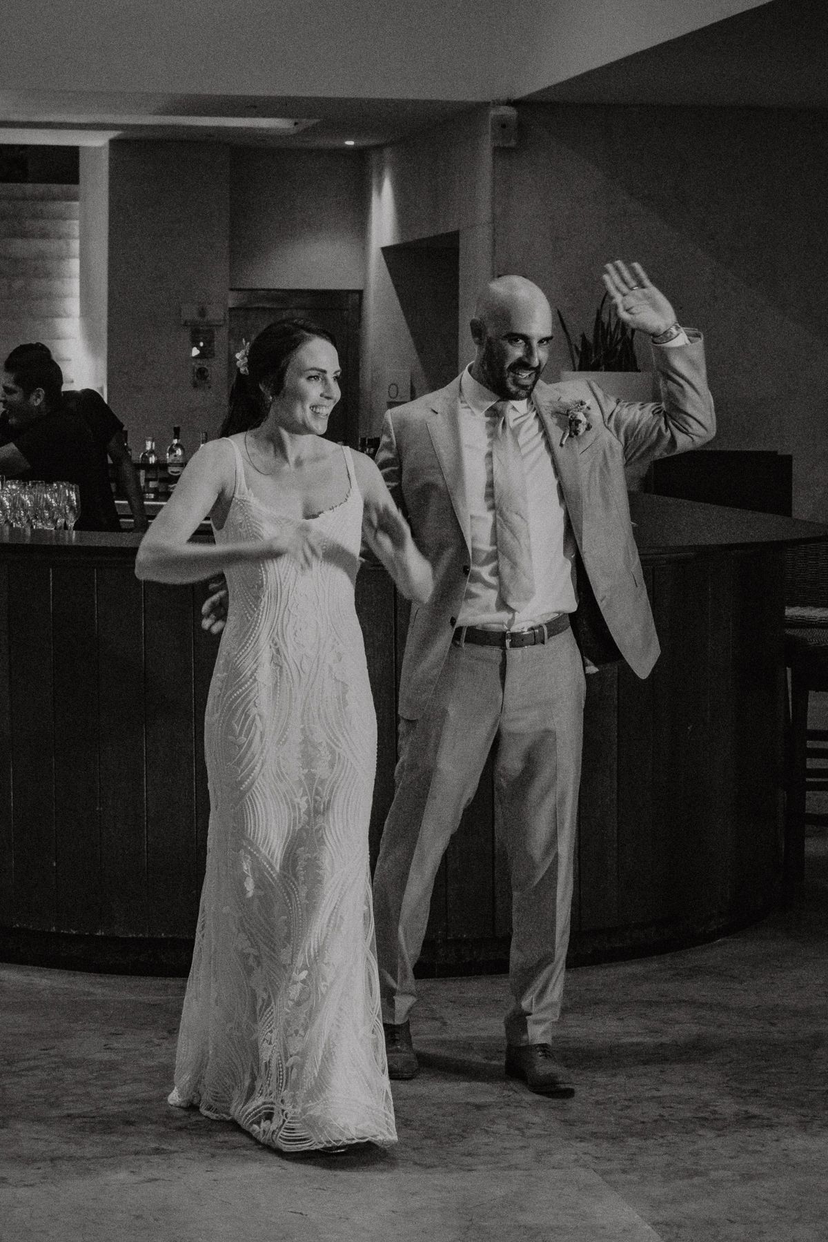 Bride and groom make a grand entrance at their wedding reception in black and white photo.