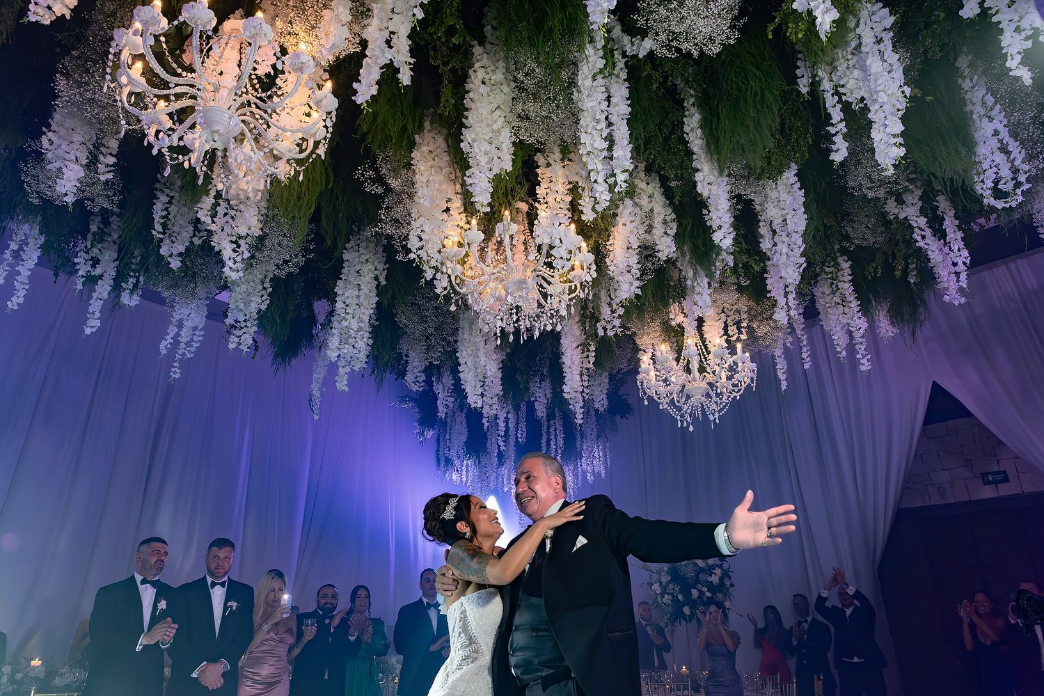 Elegant wedding reception venue decorated with cascading white floral arrangements and crystal chandeliers creating a dreamy atmosphere.