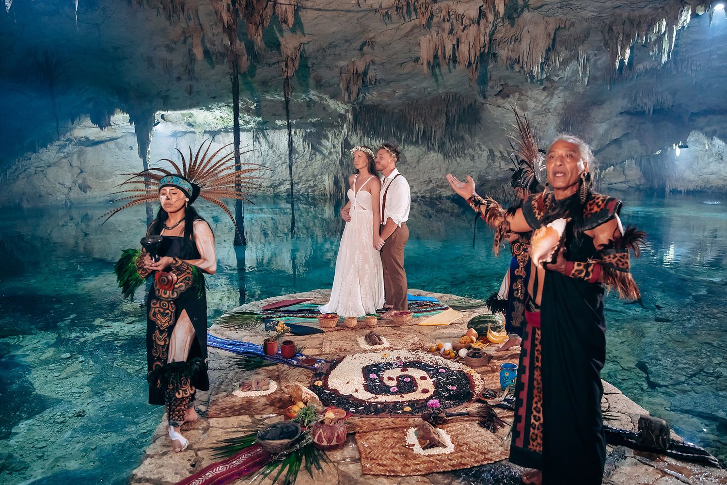 An elegant cave reception setup with food displays and ambient lighting among limestone formations.