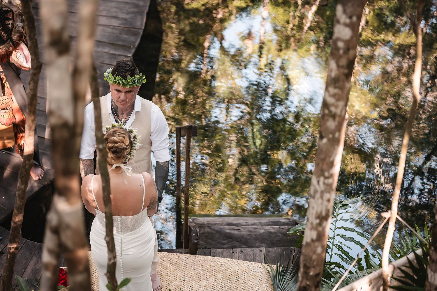 Intimate wedding ceremony taking place in a natural cave setting surrounded by tropical foliage.