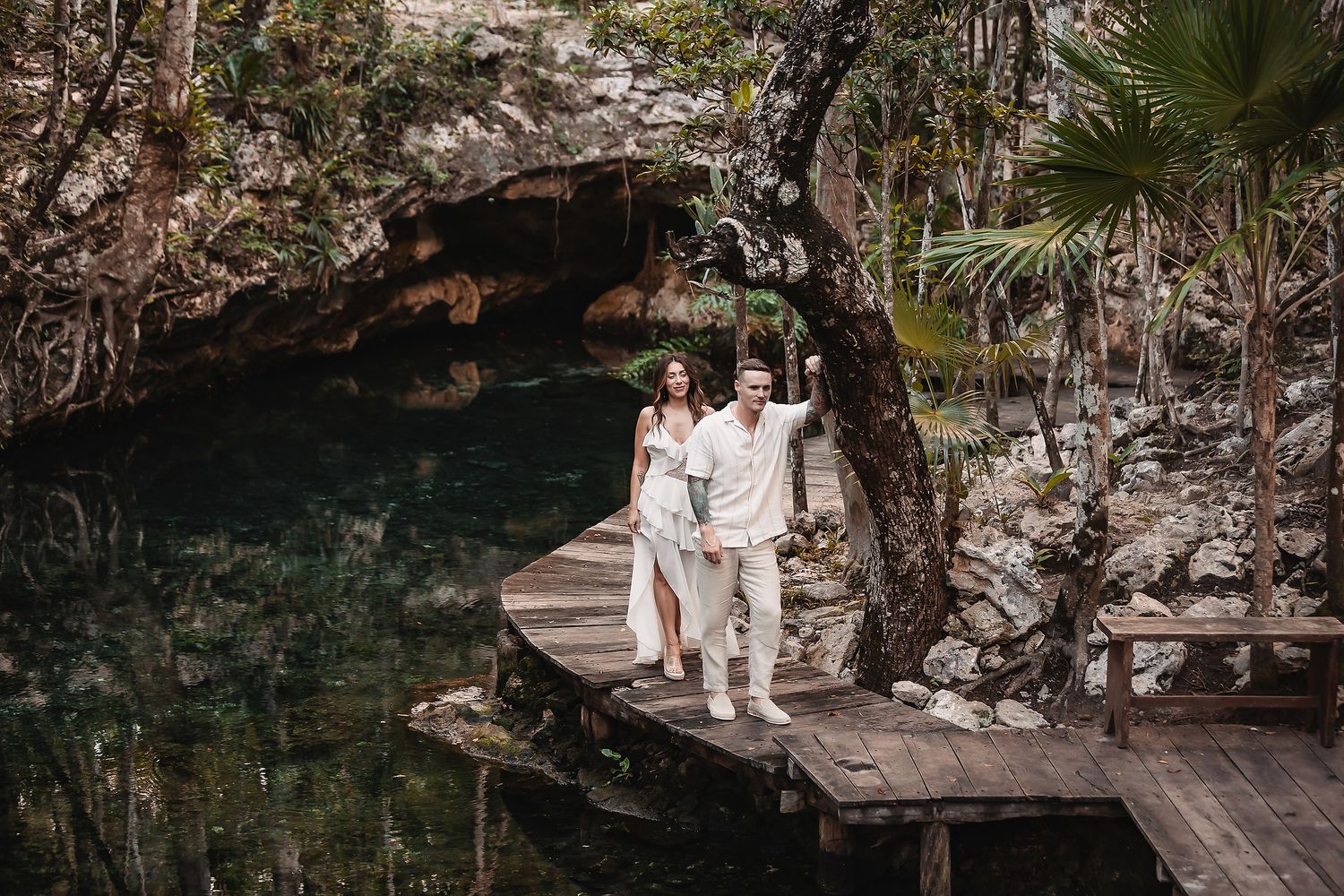 Romantic outdoor setting with wooden deck and stone walls surrounded by lush greenery.