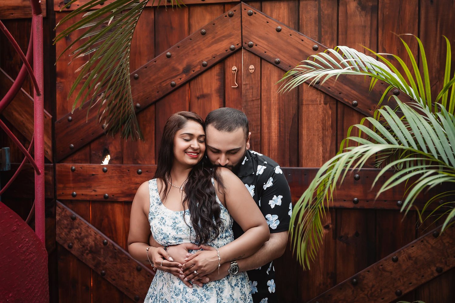 A joyful embrace captured in front of a rustic wooden backdrop.