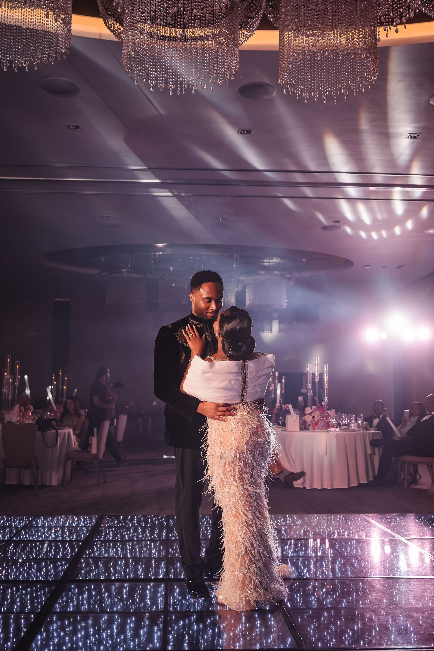 Romantic dance scene with crystal chandeliers and dramatic lighting in an elegant ballroom setting.