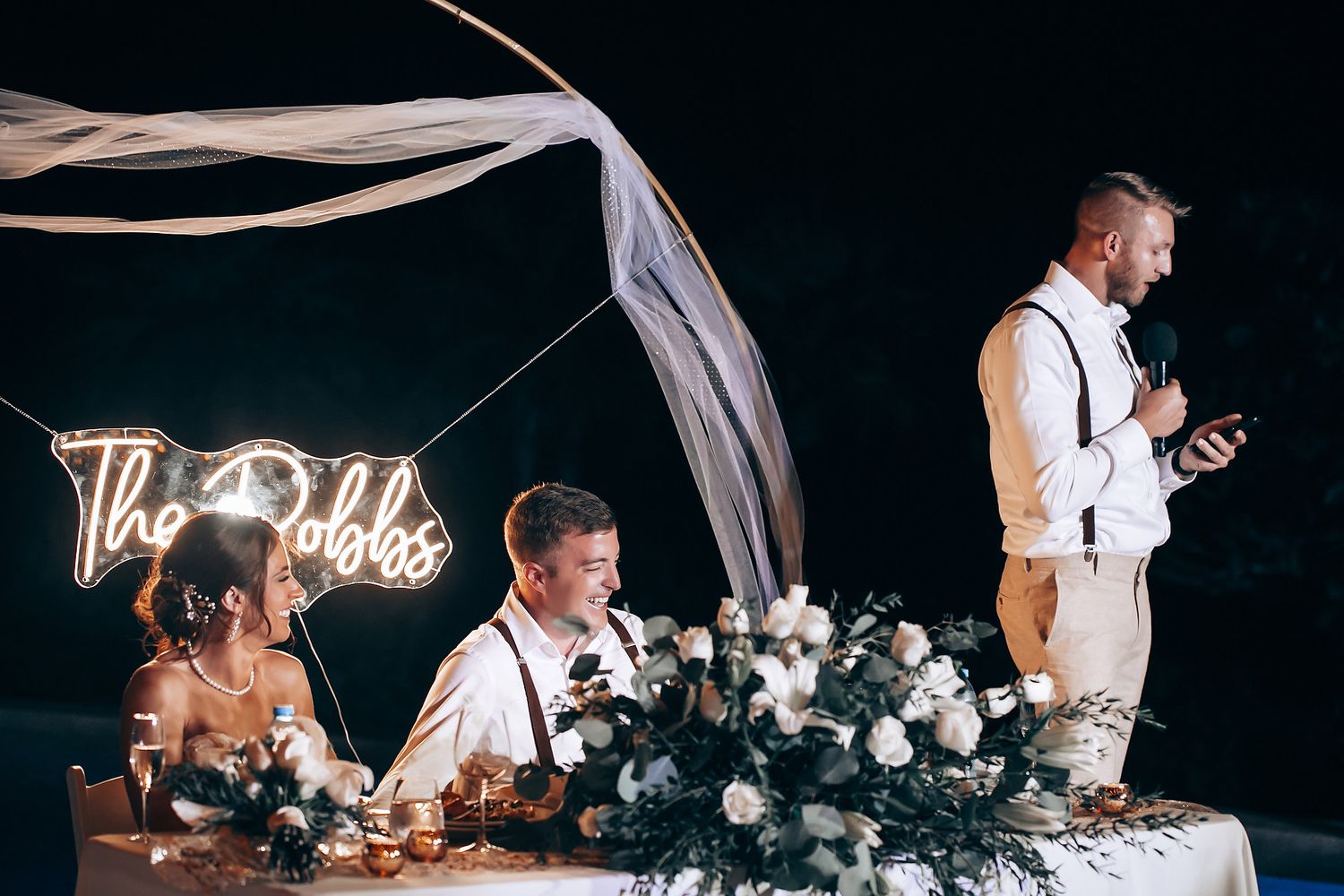 Evening wedding reception with elegant table settings and romantic lighting.