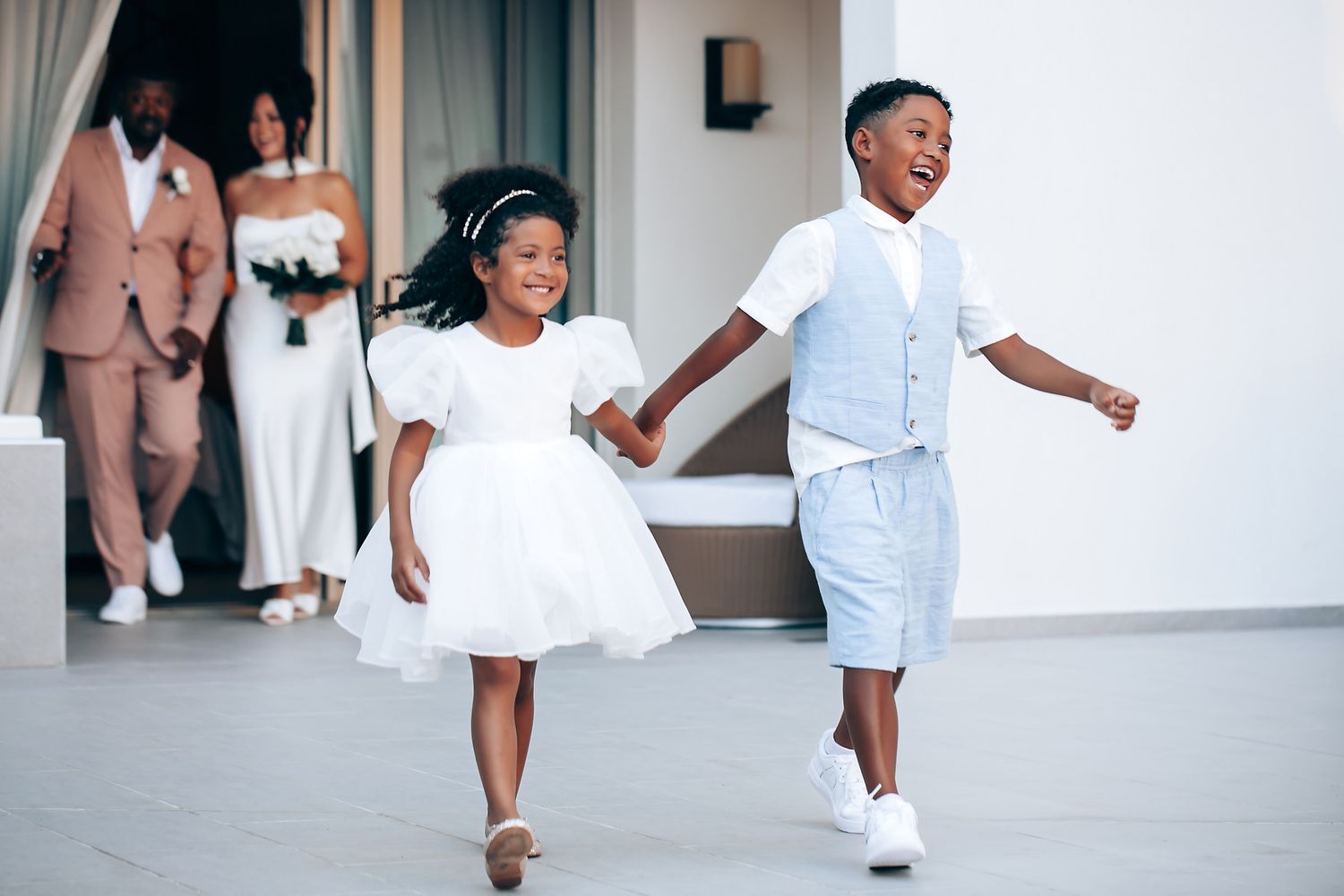 Children in white outfits running and playing during a wedding celebration.