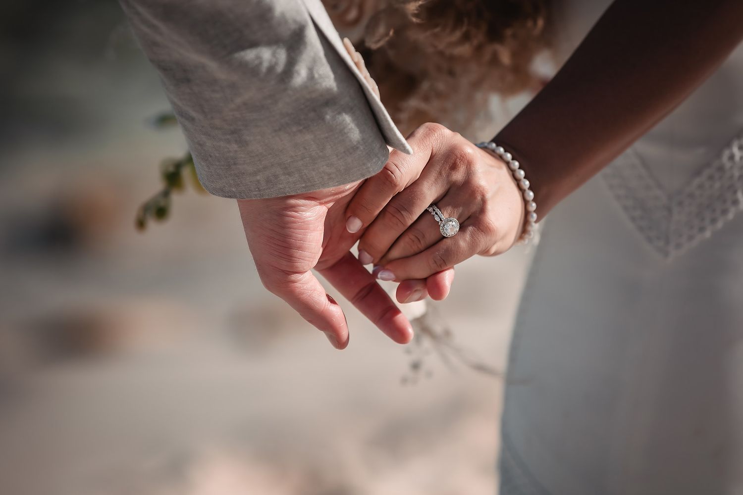 Close-up of hands showing wedding rings and bridal details.