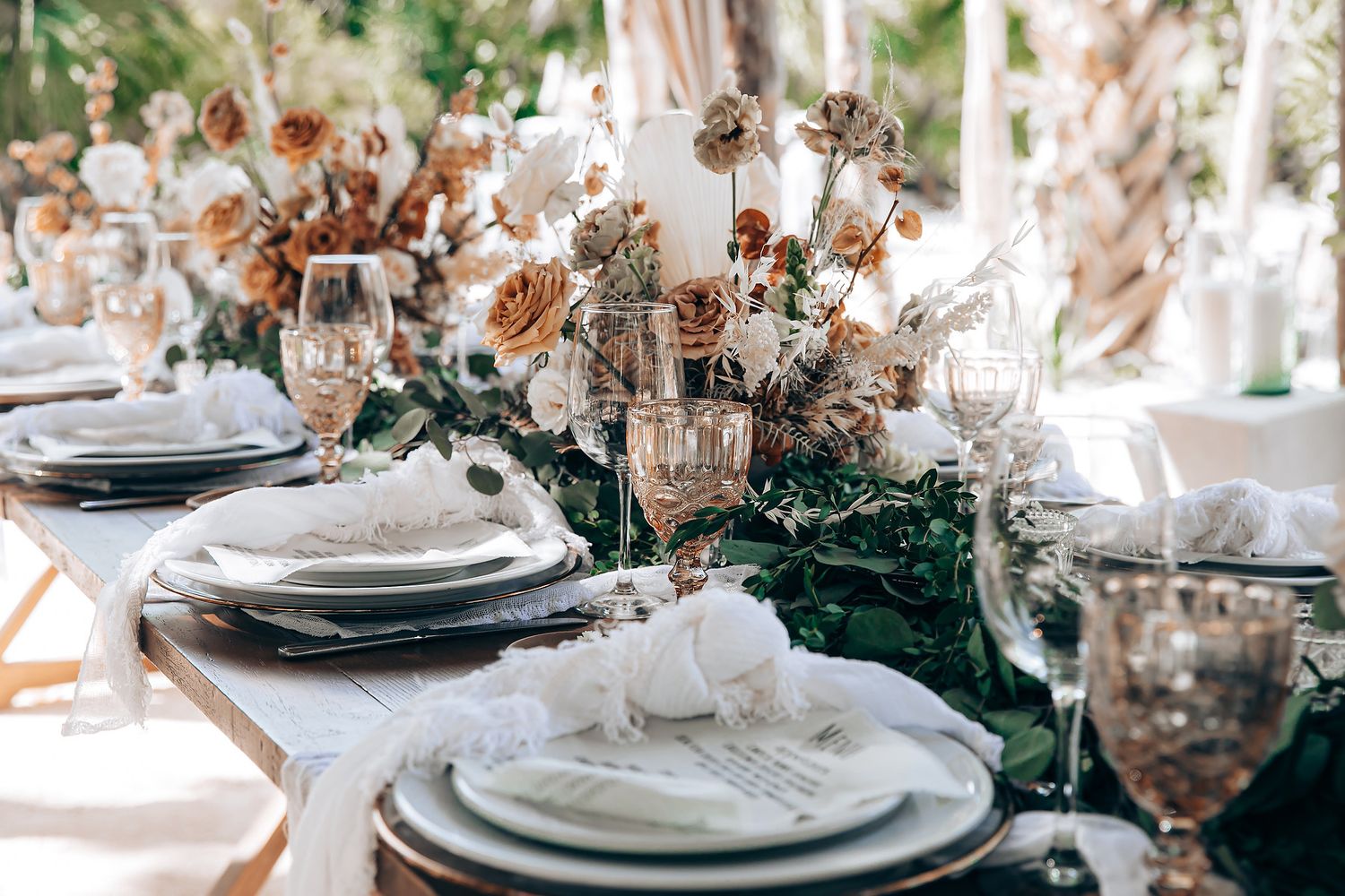Elegant table setting with white plates, blush floral arrangements, and crystal glassware for a romantic wedding reception.