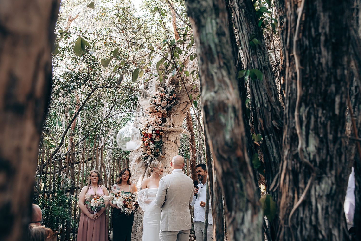 A couple shares a romantic moment in a forest setting during their wedding ceremony.
