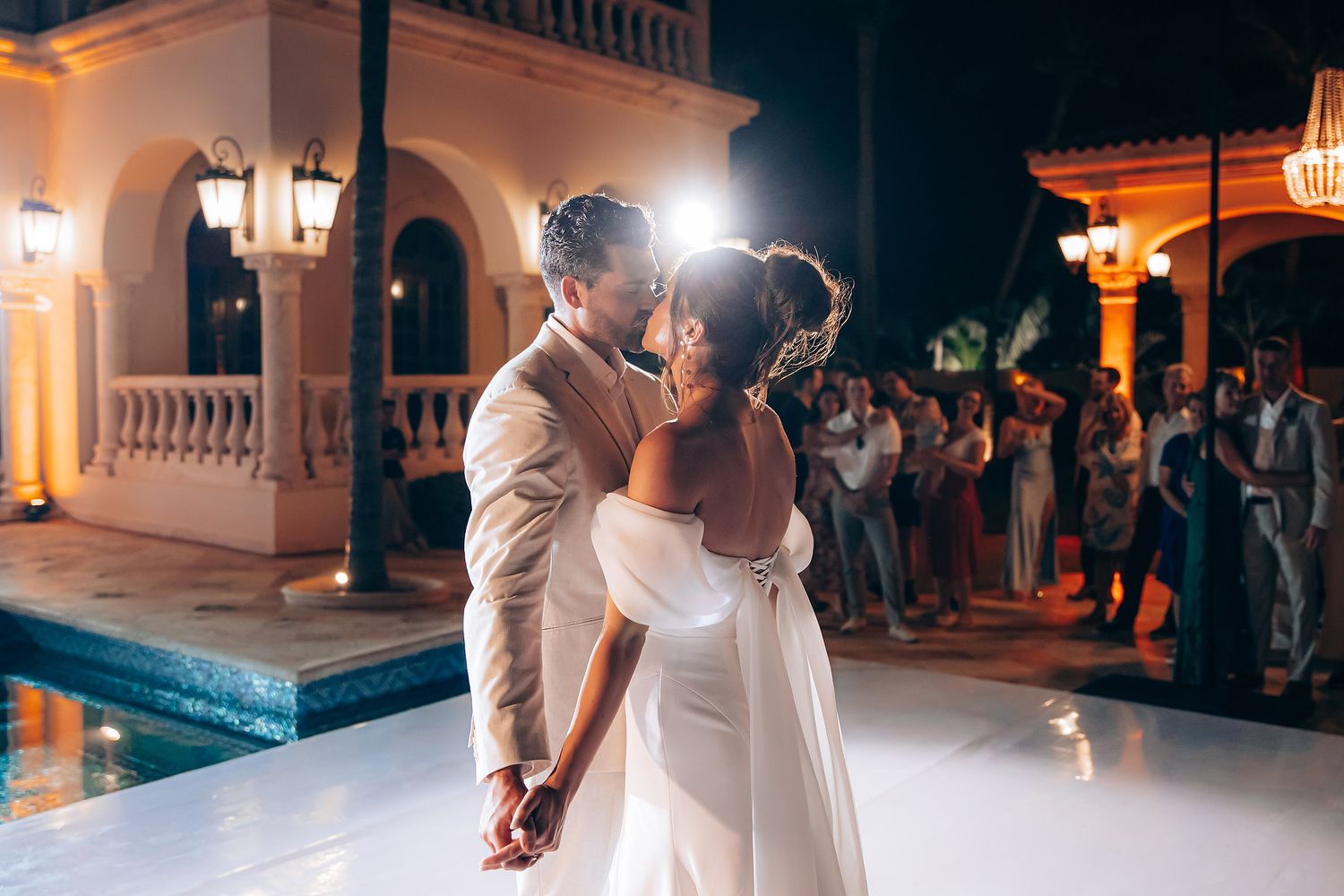 A couple shares a romantic dance at their wedding reception as guests watch in the background.