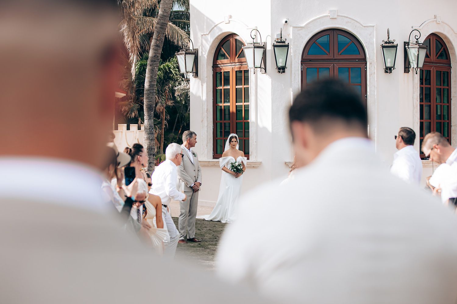 A wedding couple and guests celebrate during an outdoor ceremony in front of a white church building.