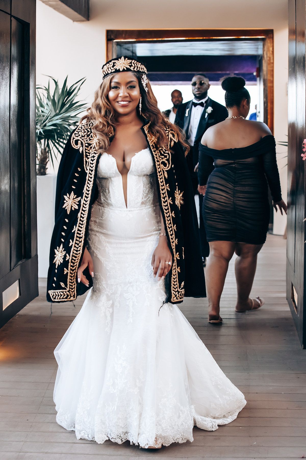 Wedding party walking through a modern hallway with white walls and wooden beams.