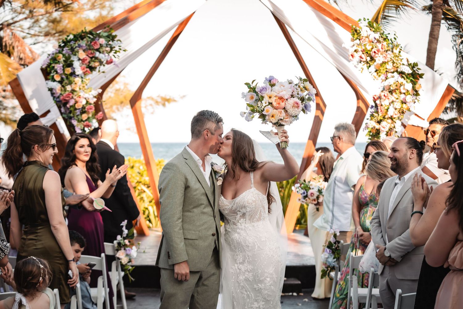 Wedding ceremony with orange and floral decorations under an outdoor canopy.