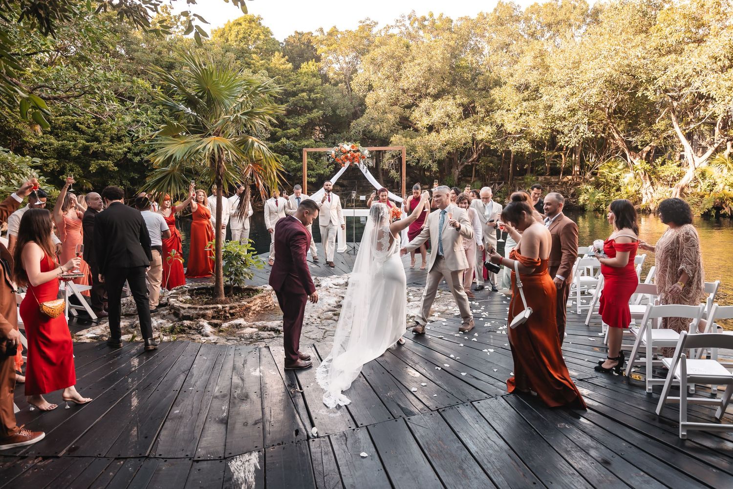Panoramic view of outdoor wedding ceremony with guests in burgundy and white attire.