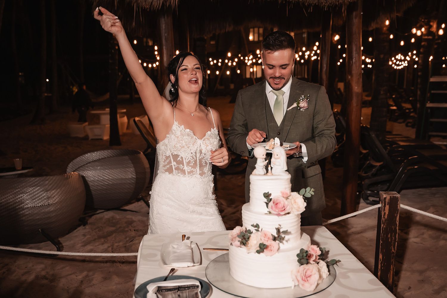 Bride and groom share a special moment while cutting their wedding cake at night.
