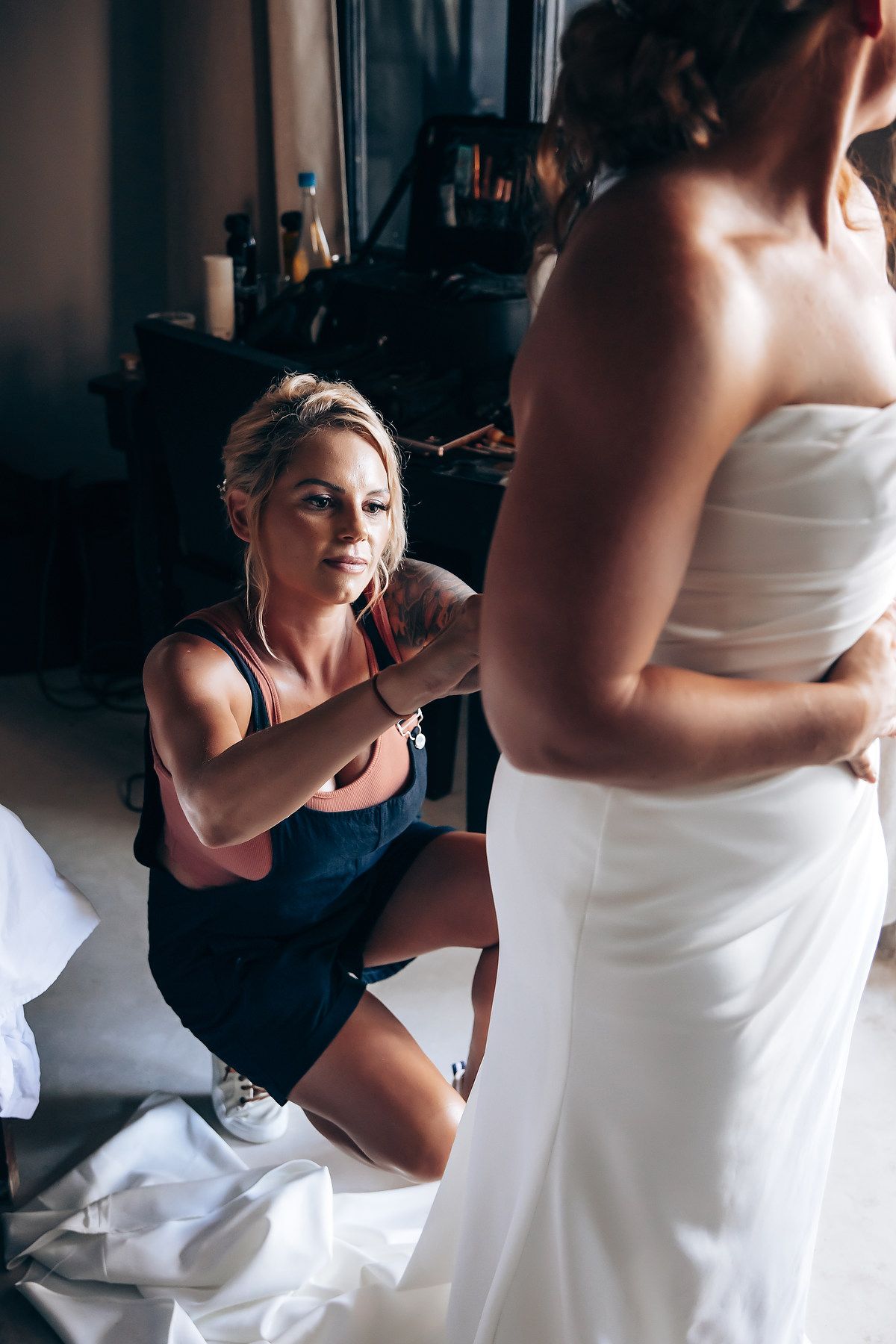 Getting ready scene with white dress preparations in dimly lit room.