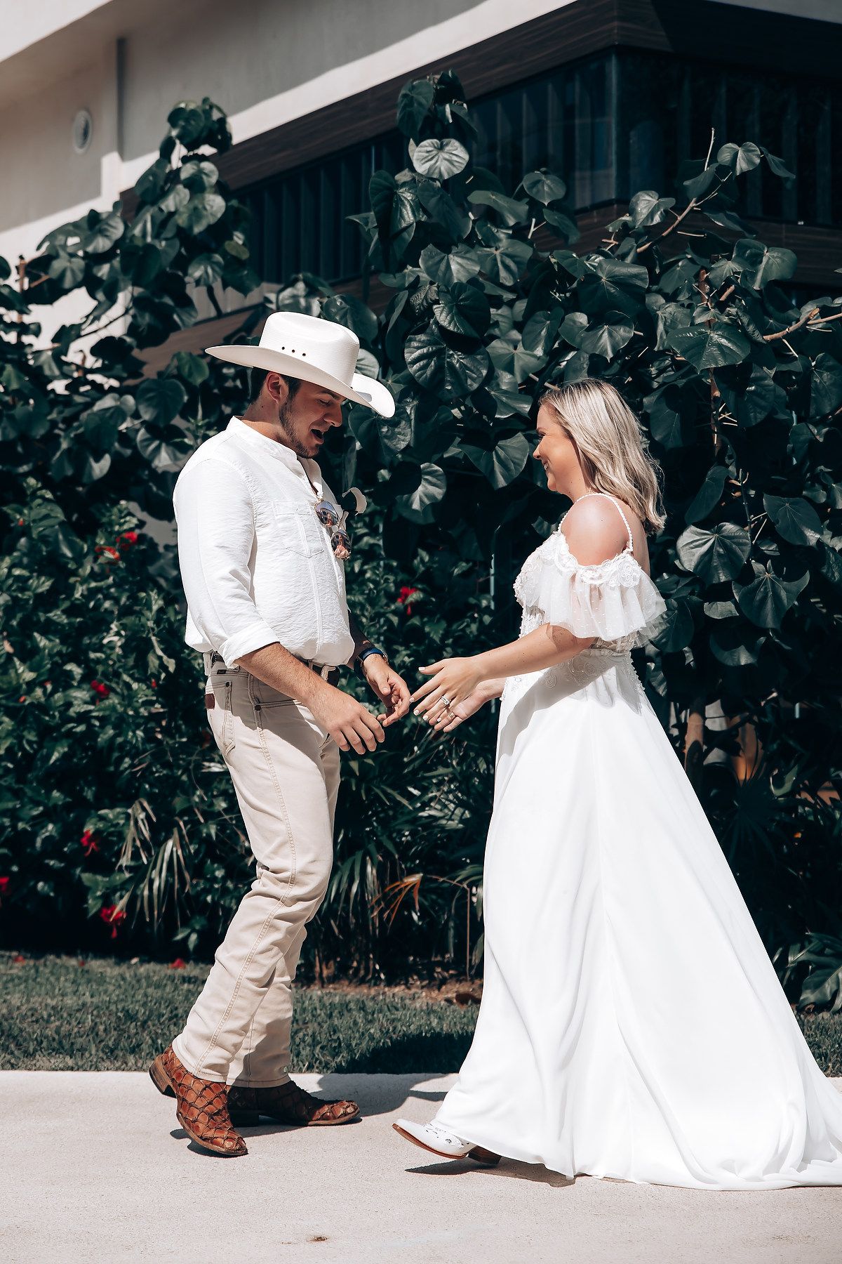 A couple in western attire shares a playful dance moment outdoors.