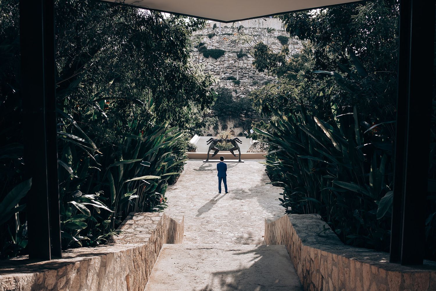 Stone pathway through trees leading to outdoor wedding ceremony location.