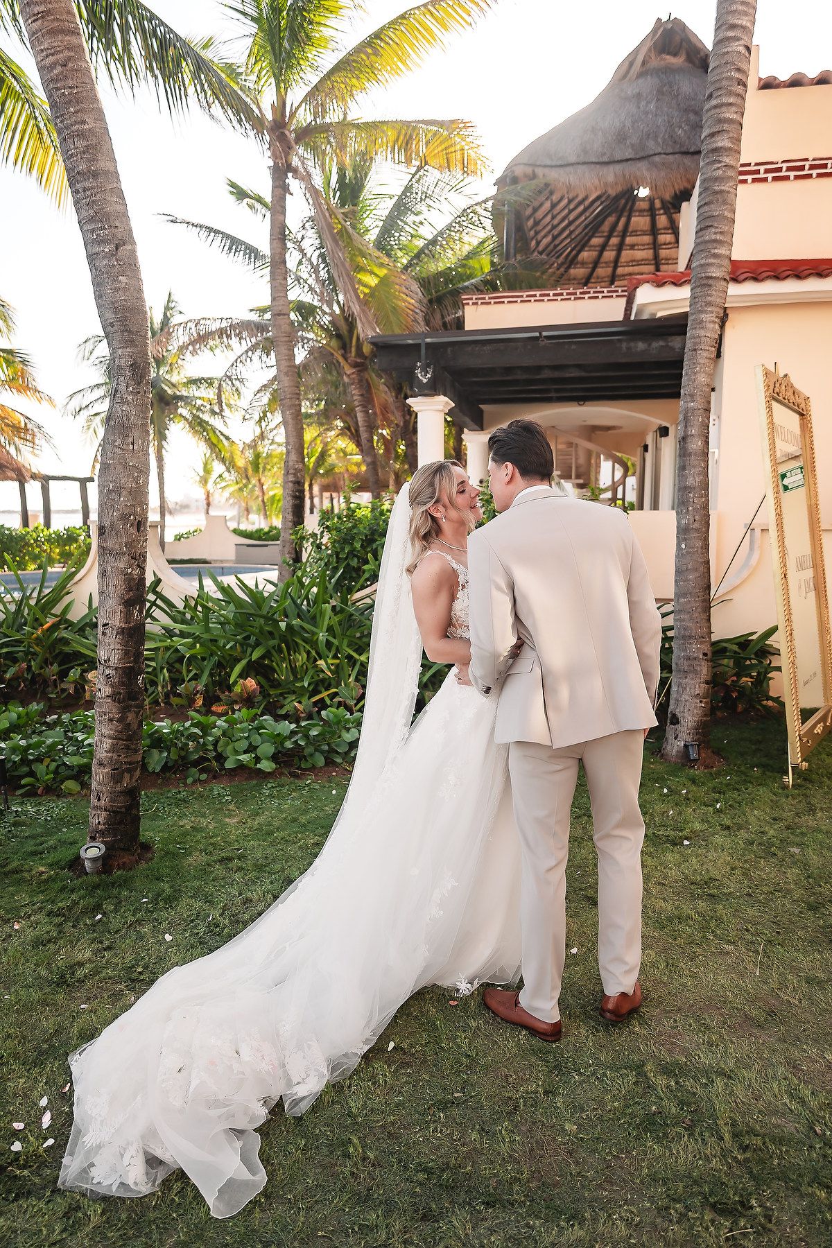 Newlyweds share intimate moments among palm trees in a tropical garden setting.