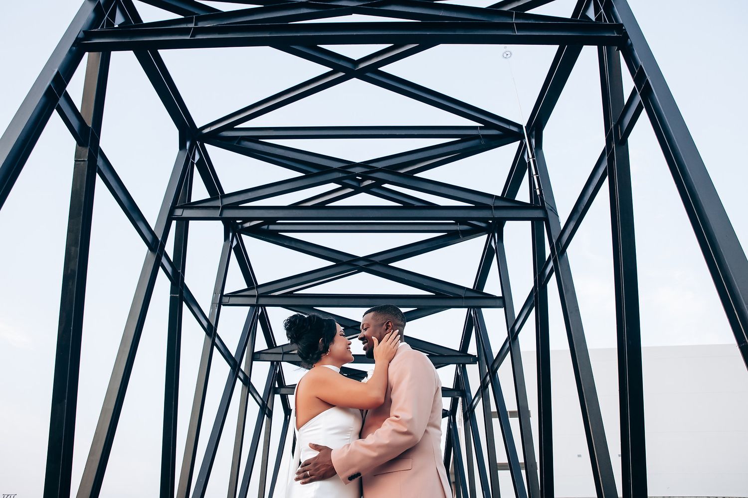 A steel bridge structure photographed against a bright sky.