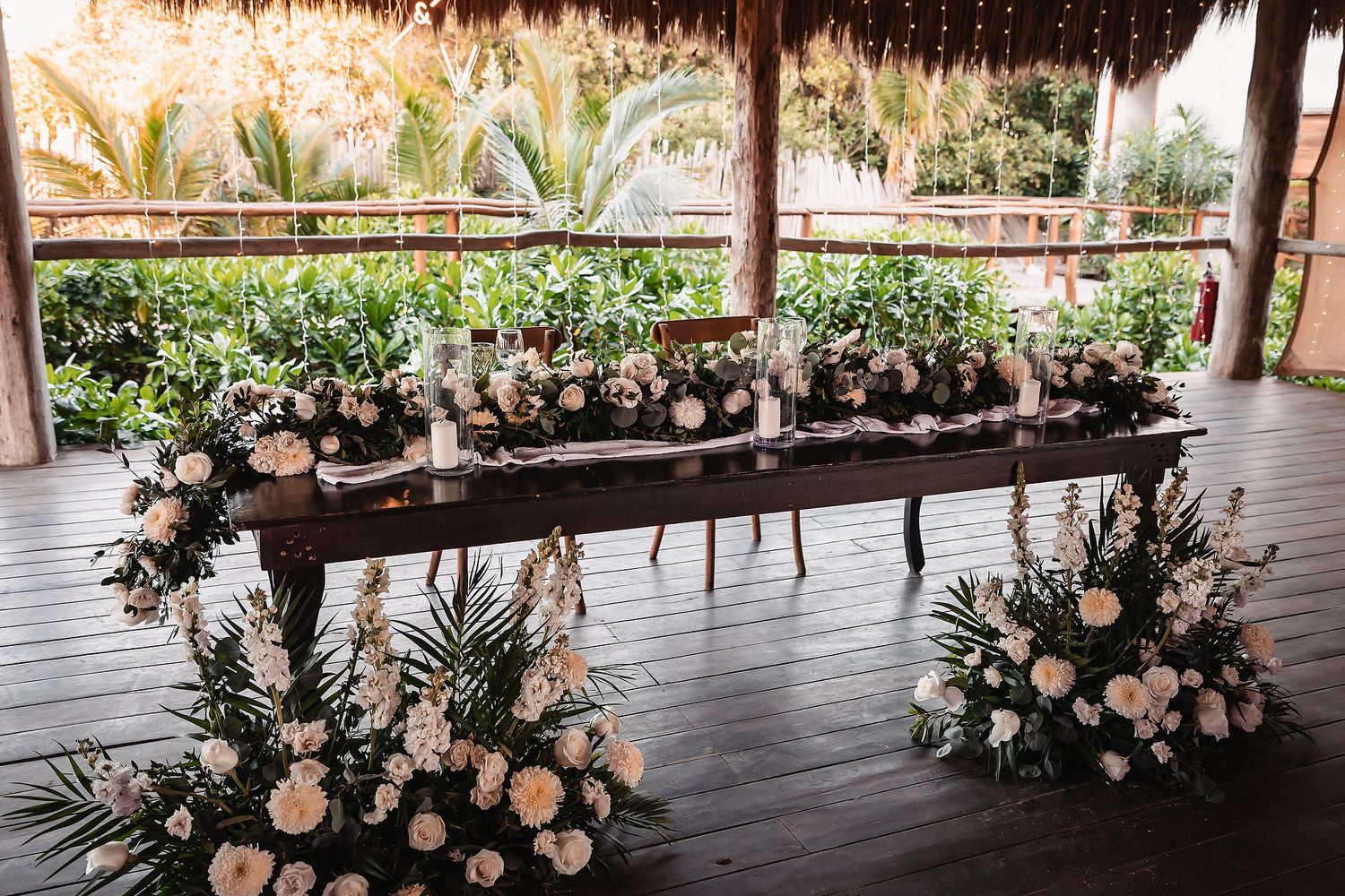 Panoramic view of a beach wedding venue with palm trees and floral decorations.