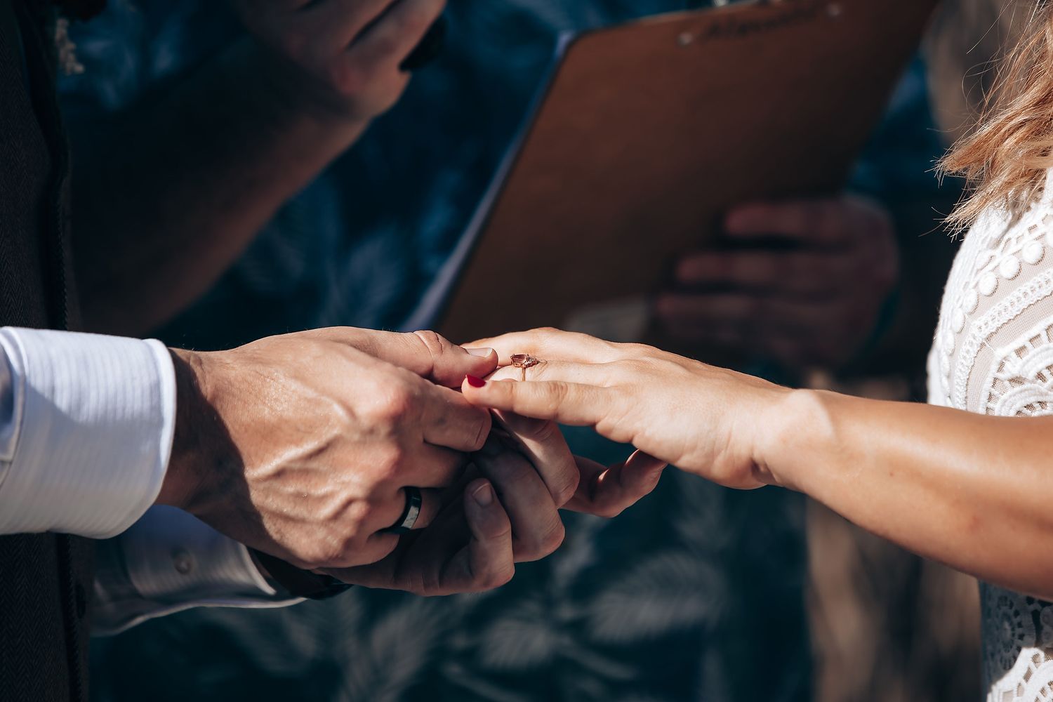 Hands exchanging rings during an intimate wedding ceremony moment.
