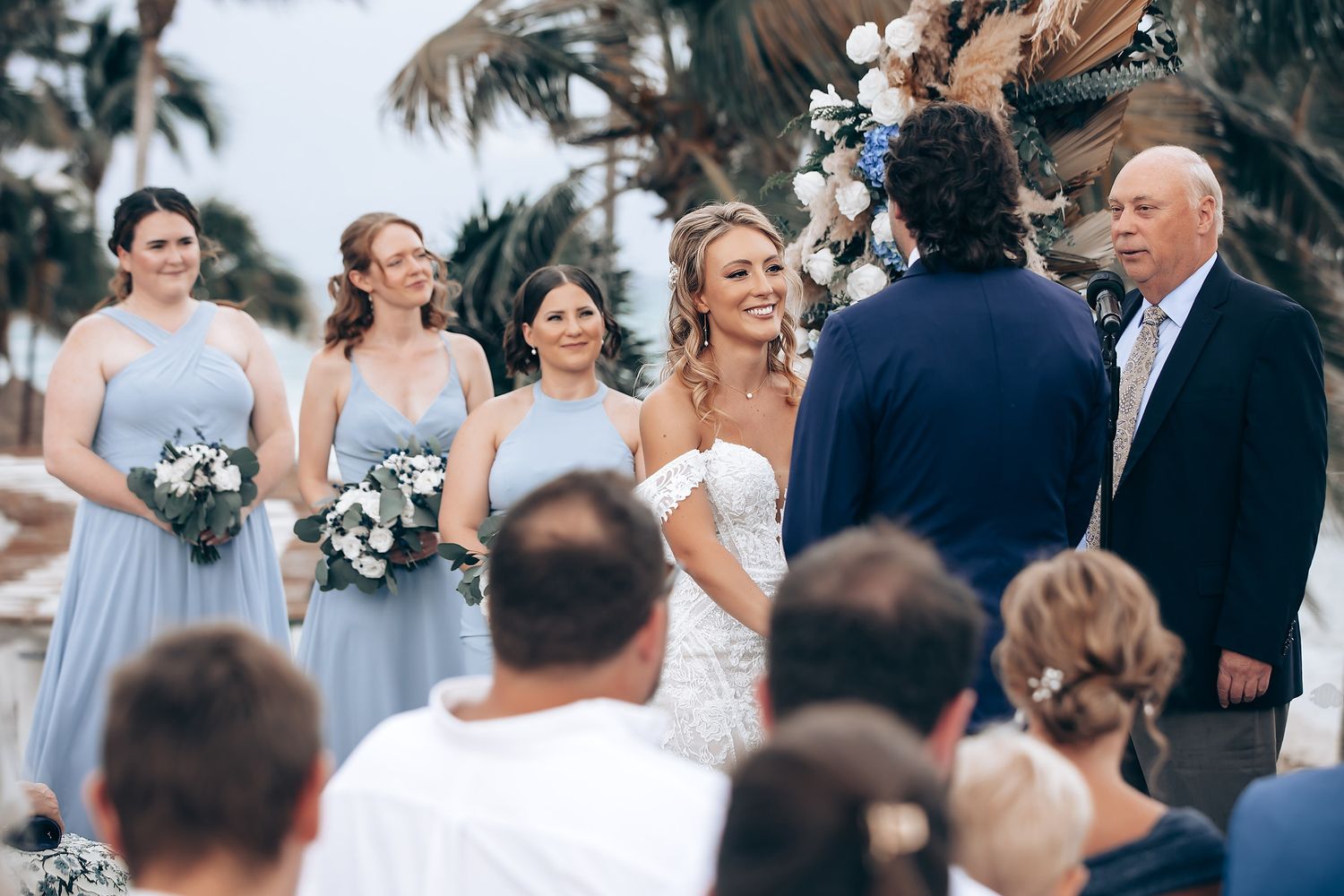 Elegant outdoor wedding ceremony setup with white chairs and tropical palm trees in the background.