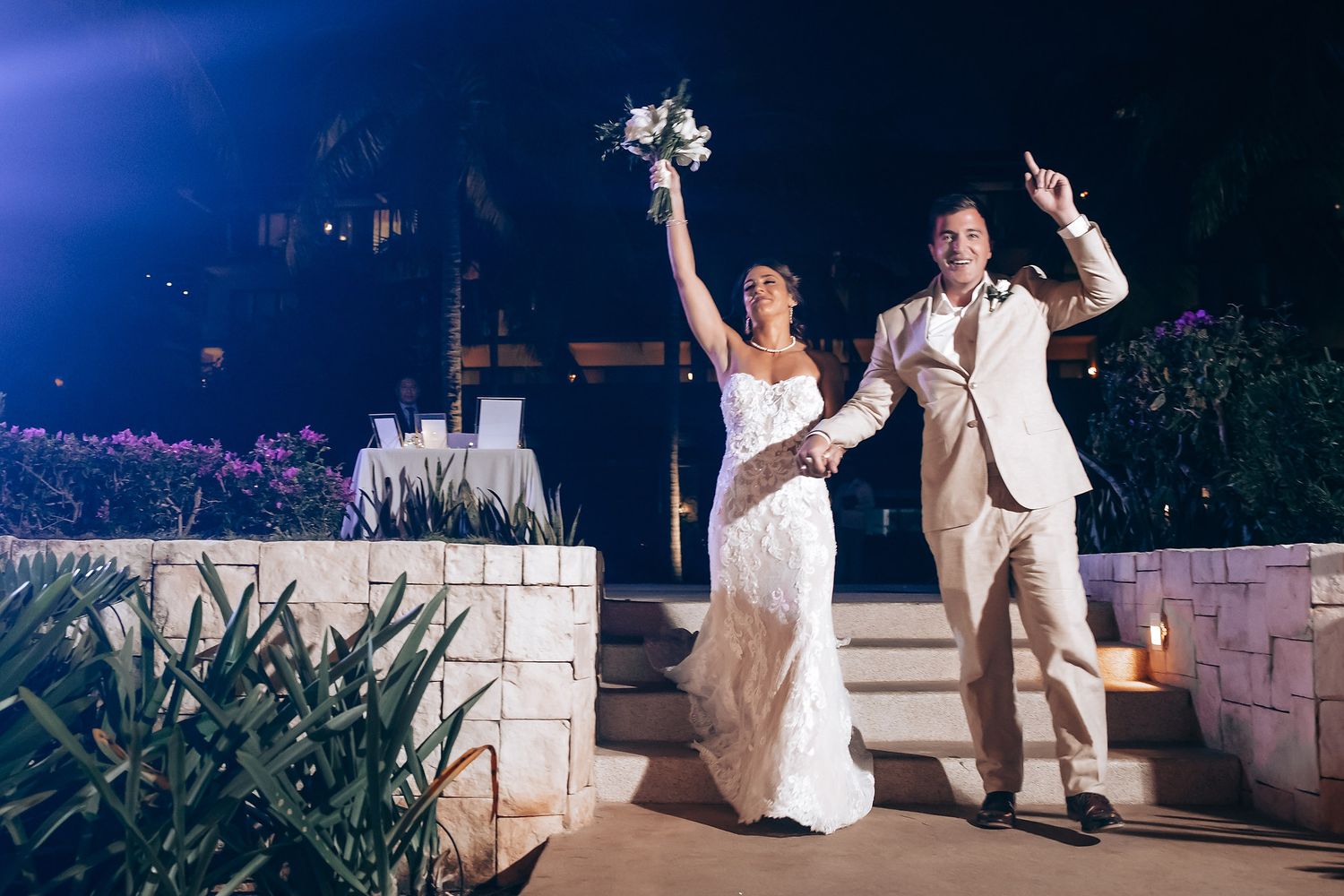 Newlyweds share a romantic dance under twinkling lights at their outdoor evening reception.